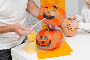 Holiday preparation and handmade party decor. Halloween family indoor activity, pumpkin painting process