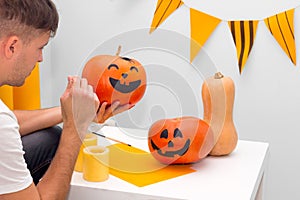 Holiday preparation and handmade party decor. Halloween indoor activity, pumpkin painting process