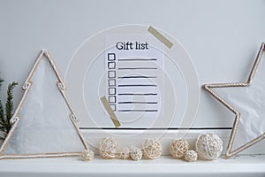 Holiday preparation paper note with GIFT LIST checklist text. Vision board wall with cozy minimalistic handmade new year
