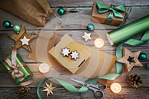 Holiday preparation, wrapping gifts with natural paper and green ribbon, Christmas decoration like balls, stars and lit candles on