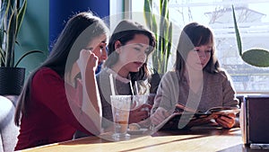 Holiday in restaurant, company lady watch of menu with latte at table