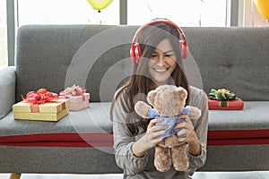 Holiday Seasonal and Happy Concept. Portrait of beautiful young asian woman with headphone smiling and holding a cute bear doll in