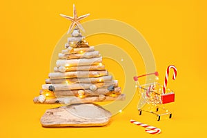 Holiday shopping. A toy empty shopping carts, and a craft wooden Christmas tree. Copy space. Concept of Christmas sales