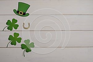 Holiday St. Patrick`s Day. Green hat with clover and horseshoe on a white wooden background with copy space