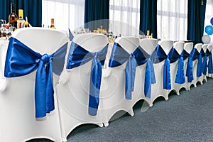 Holiday table surrounded by white chairs with blue bows