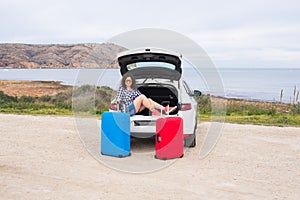 Holiday, travel and tourism concept - young woman with suitcases on car trip