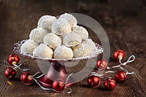 Holiday treat, Russian Teacakes stacked on a red cake plate with red jingle bell lights on a rustic wood table