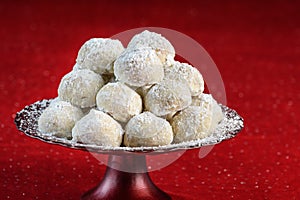 Holiday treat, Russian Teacakes stacked on a red cake plate, on a red velvet tablecloth