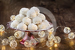 Holiday treat, Russian Teacakes stacked on a red cake plate with silver wire ball lights on a rustic wood table