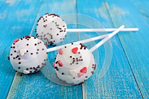 Holiday treats. Cake pops. Biscuit cakes in white chocolate glaze on a bright blue wooden background