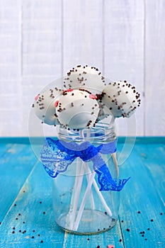 Holiday treats. Cake pops. Biscuit cakes in white chocolate glaze on a bright blue wooden background.