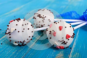 Holiday treats. Cake pops. Biscuit cakes in white chocolate glaze on a bright blue wooden background