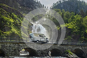 Holiday trip in motorhome, Caravan car Vacation. RV traveling on the road Latefossen Waterfall Odda Norway. Latefoss is a powerful