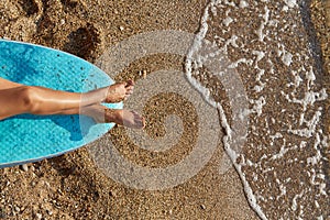 Holiday trip, summer time and time to relax idea, copy space. Womans legs getting tanned on sun. Wet sand on coastline.