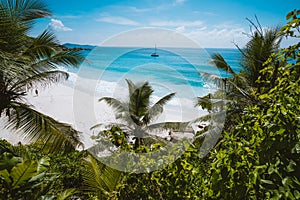 Holiday vacation at Petite Anse paradise beach framed by green foliage. La Digue island, Seychelles