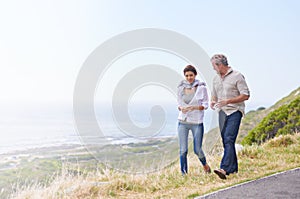 Holiday, walk and mature couple on road at the beach in countryside or nature with conversation of retirement. Summer