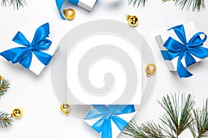 Holiday winter background. White gift box with blue ribbon, New Year balls and Christmas tree in xmas composition on white for