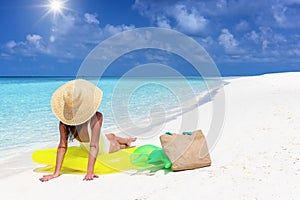 A holiday woman with a hat sits on a yellow inflatable at a tropical paradise beach