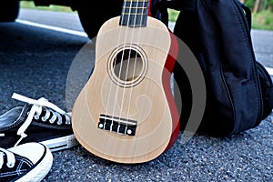 On holiday, wooden floor color ukulele with bag.