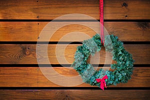 Holiday wreath hanging against wood planks