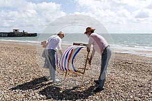 Holidaymakers erecting a deckchair on the beach