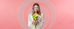 Holidays, beauty and spring concept. Portrait of lovely, romantic blonde girl in white dress, holding yellow tulips
