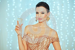 Holidays, celebration and people concept - smiling woman with fashionable makeup, elegance wave on hair in gold dress with glass