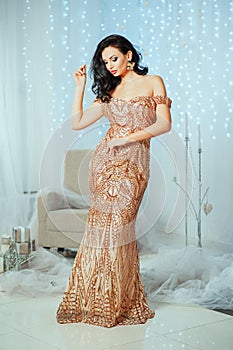 Holidays, celebration and people concept - smiling woman with fashionable makeup and elegance wave on hair in gold dress over