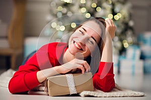 Holidays, celebration and people concept - smiling woman wearing red sweather and jeans holding gold gift box over