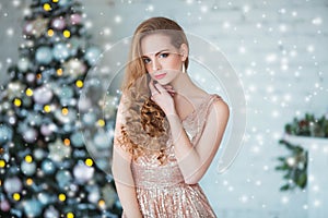 Holidays, celebration and people concept - young woman in elegant dress over christmas interior background