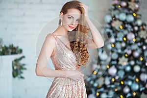 Holidays, celebration and people concept - young woman in elegant dress over christmas interior background