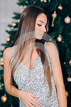 Holidays, celebration and people concept - young woman in elegant dress over christmas interior background