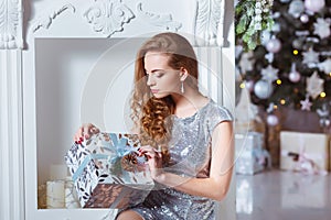 Holidays, celebration and people concept - young woman in elegant dress over christmas interior background