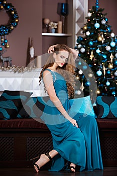 Holidays, celebration and people concept - young woman in elegant dress over christmas interior background.