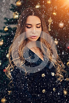 Holidays, celebration and people concept - young woman in elegant dress over christmas interior background. Winter, snow