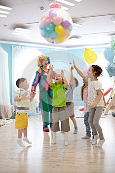 Holidays, childhood and celebration concept - several kids having fun and jumping on birthday party in entertainment