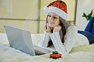Holidays christmas interior winter concept. young woman in cozy bedroom with laptop computer lying on bed at home. Close