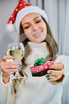 Holidays christmas winter concept. young woman with laptop computer at home and holding a red gift in his hand.