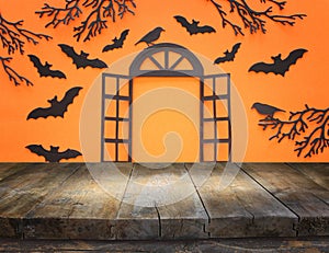 Holidays concept of Halloween. Empty rustic table in front of open window and bats over orangr background. Ready for product