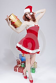 Holidays Concept and Ideas. Happy Smiling Caucasian Red Haired Santa Helper Holding Golden Gift in Hand