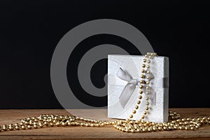 Holidays decoration gift box with golden perls on black background
