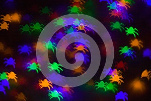 holidays, decoration and party concept - defocused bokeh multicolor lights in shape of spiders for halloween background