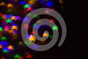 holidays, decoration and party concept - defocused bokeh multicolor lights in shape of spiders for halloween background