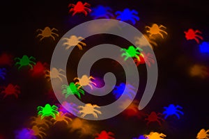 holidays, decoration and party concept - defocused bokeh multicolor lights in shape of spiders for halloween background