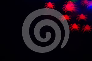 holidays, decoration and party concept - defocused bokeh red spiders silhouette on black for halloween background