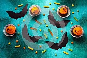 Holidays, decorations and party concept - Halloween cupcakes and candies on green background