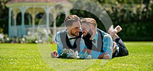 Holidays, Festivals, and Events lgbt concept. Gay marriage couple laying on grass on wedding day.