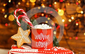 Holidays. Festive bokeh. Christmas mug with hot drink and candy cane.