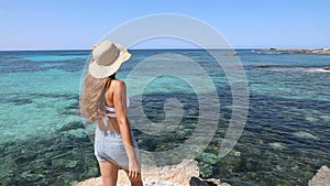 Holidays and freedom concept. Beautiful woman enoying wind on small pristine island in the Mediterranean sea. Copy space.