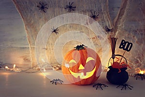 Holidays halloween concept image. Pumpkin, spiders over wooden table